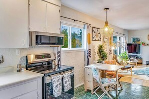 A modern kitchen with a built-in oven, microwave, and a dining area with a table and chairs. - Boho-Chic Seattle Home | Walk to Gas Works & More (Seattle)