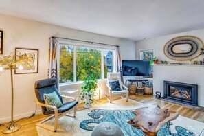 Ein modernes Wohnzimmer mit Kamin, Fernseher und großem Fenster.