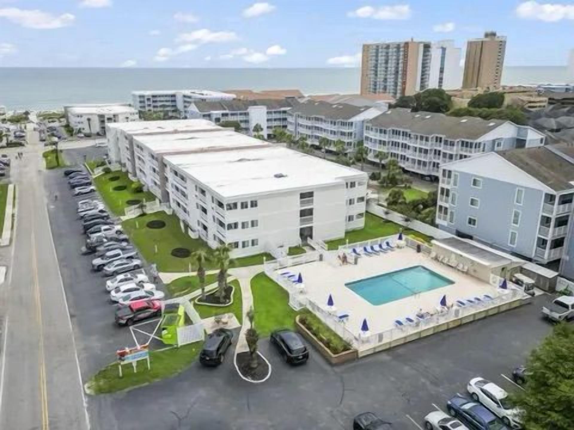 A hotel with multiple buildings, a swimming pool, and a parking lot.