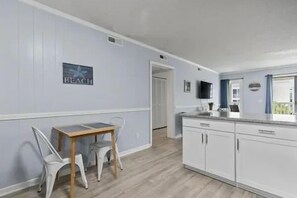 A kitchen with white cabinets, a wooden table, and chairs. - A Place at the Beach V (Horry County)