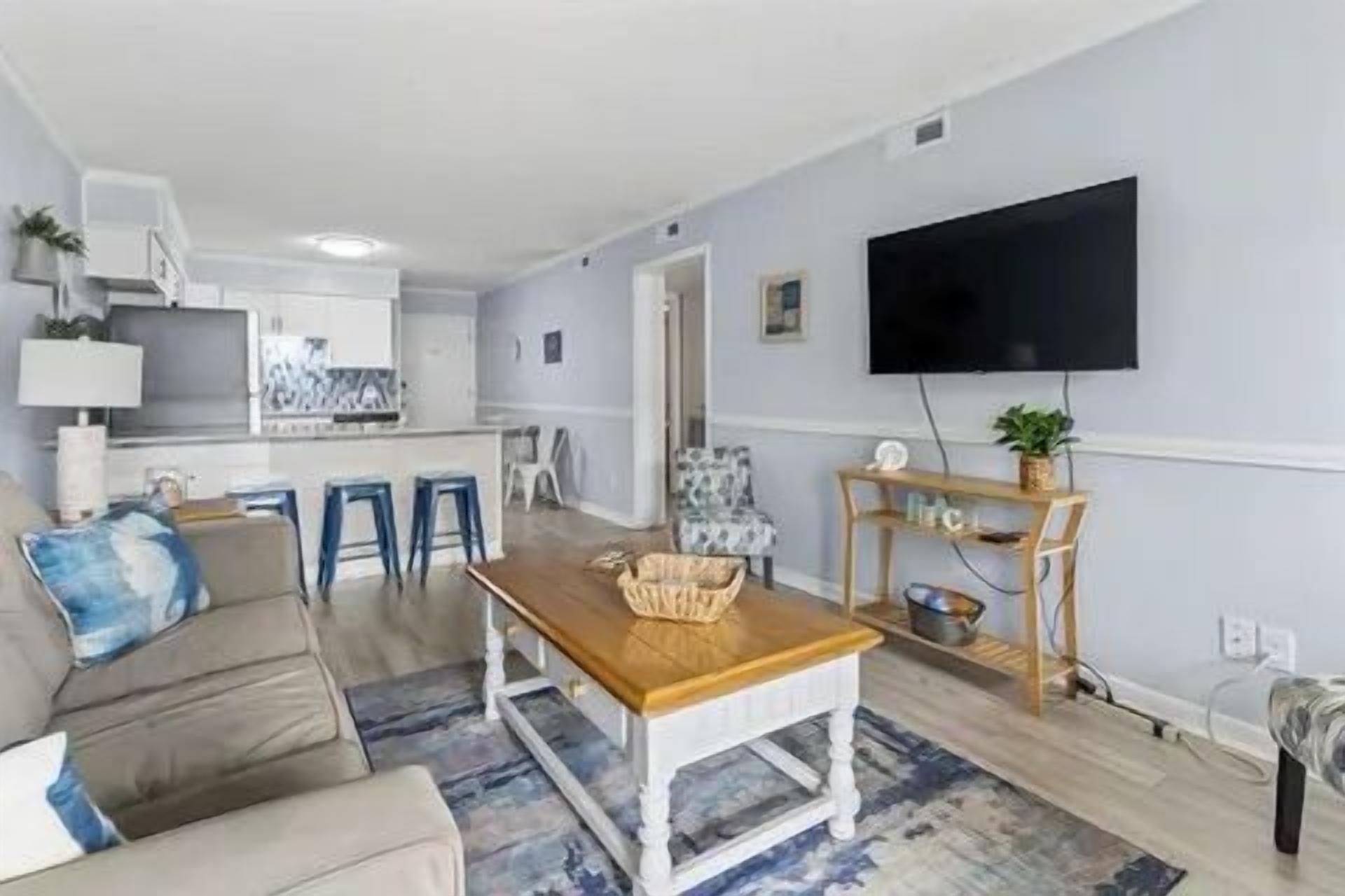 Un salon avec un canapé, une table basse et un téléviseur fixé au mur.