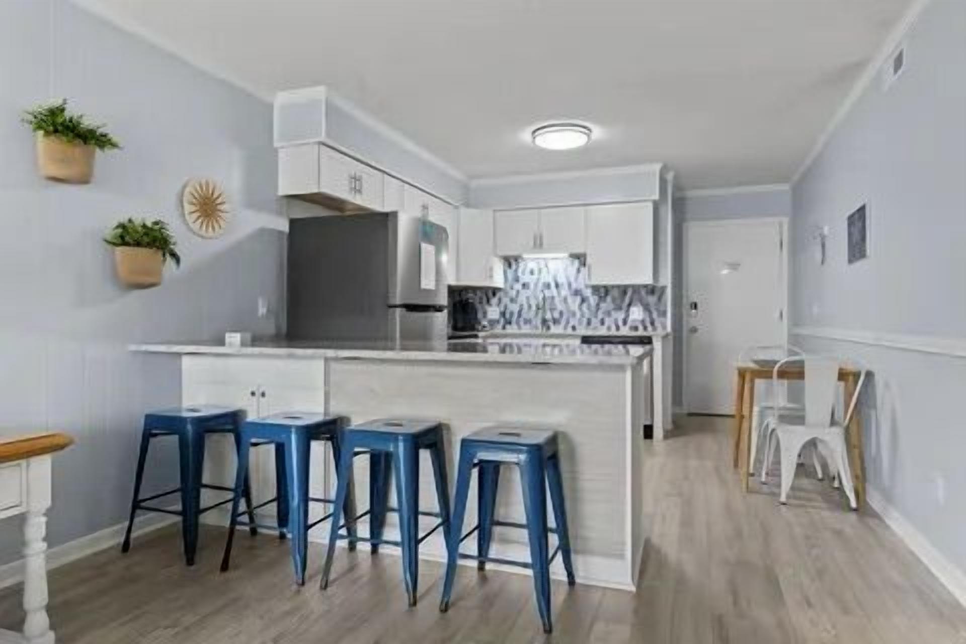 Une cuisine moderne dotée d’un îlot central, de tabourets de bar et d’un coin repas avec une table et des chaises.