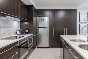 A modern kitchen with dark wood cabinets, stainless steel appliances, and a tiled backsplash. - Temple Escape 3 Bed Apartment with Private Pool (Craiglie)