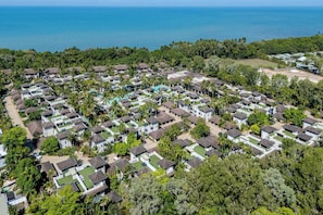 A residential area with multiple houses, some with green lawns, and a large body of water in the background. - Temple Escape 3 Bed Apartment with Private Pool (Craiglie)