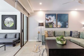 A modern living room with a grey sofa, a coffee table with a plant, and two large paintings on the wall. - Temple Escape 3 Bed Apartment with Private Pool (Craiglie)