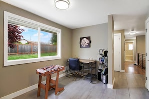A room with a foosball table, a desk with a chair, a bookshelf, and a window with a view of a backyard. - Modern Seattle Duplex, Balcony w/ Serene View (Seattle)