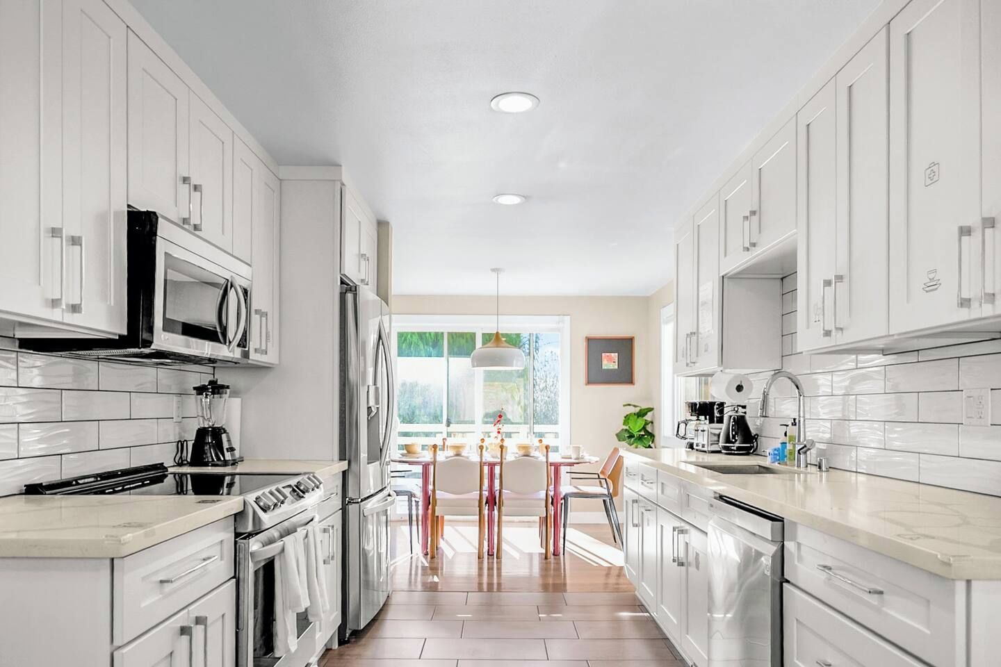 A modern kitchen with white cabinetry, stainless steel appliances, and a central island with seating.
