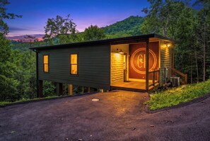 Una cabana amb una porta de vidre, un balcó de fusta i vistes a la forest circumdant.