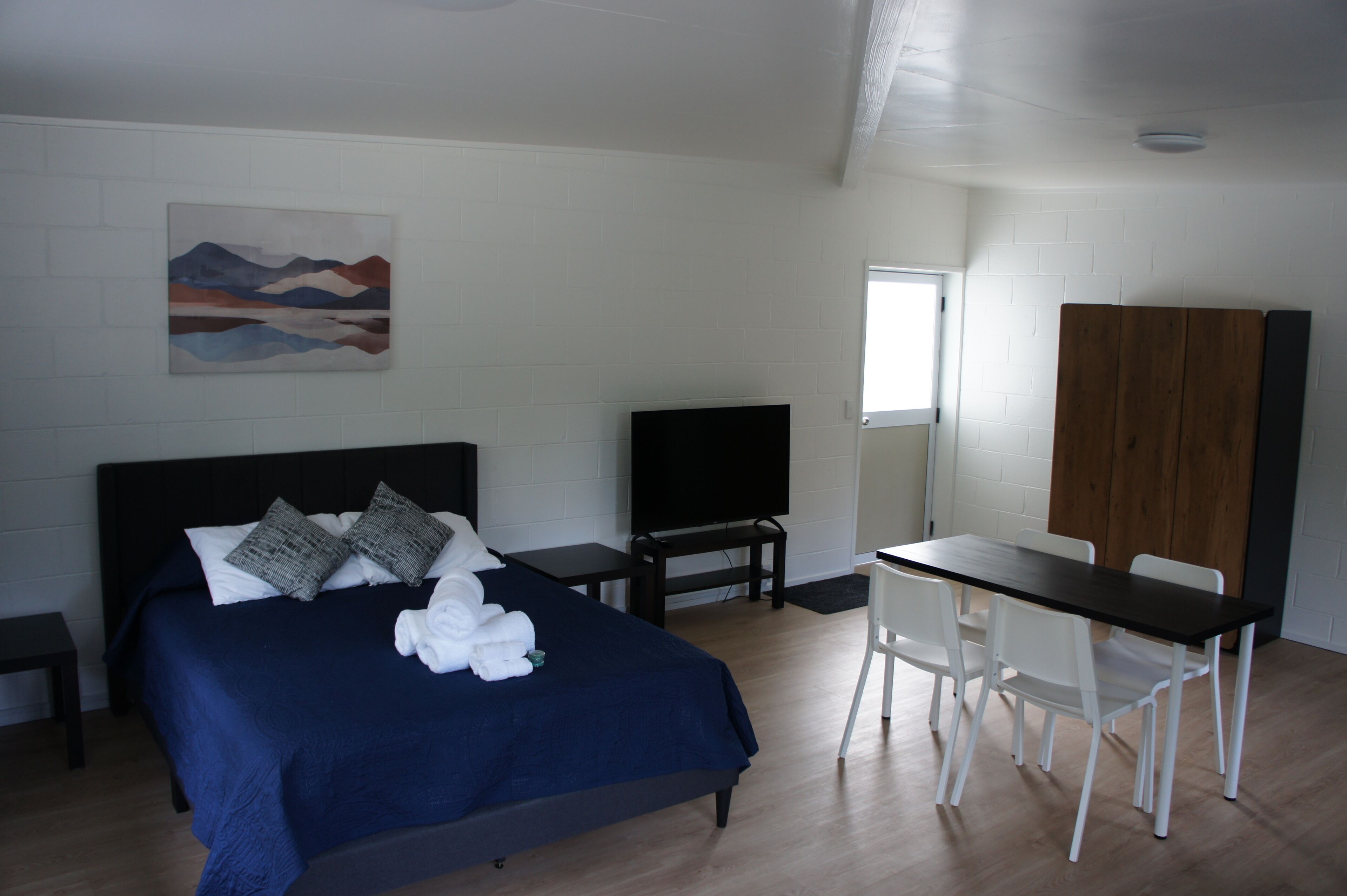 Un dormitorio con cama, televisor, escritorio y silla.