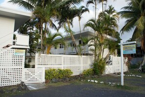 A Central Motel with a white fence, palm trees, and a modern building. - Central Motel (Rarotonga)