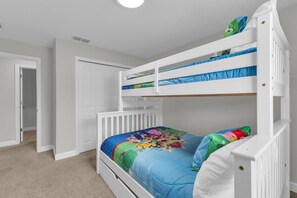 A bunk bed with a colorful bedspread, white walls, and a door in the background. - Private pool, resorts, 9 minutes to Disney (Kissimmee)