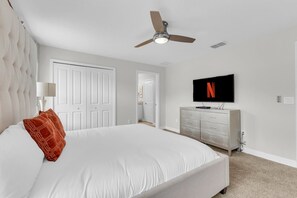 A bedroom with a large bed, a ceiling fan, a television mounted on the wall, and a dresser. - Private pool, resorts, 9 minutes to Disney (Kissimmee)