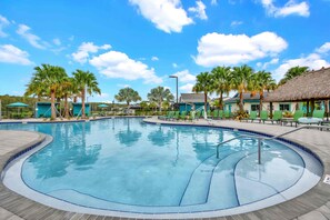 A swimming pool with a curved edge, surrounded by palm trees and lounge chairs. - Private pool, resorts, 9 minutes to Disney (Kissimmee)