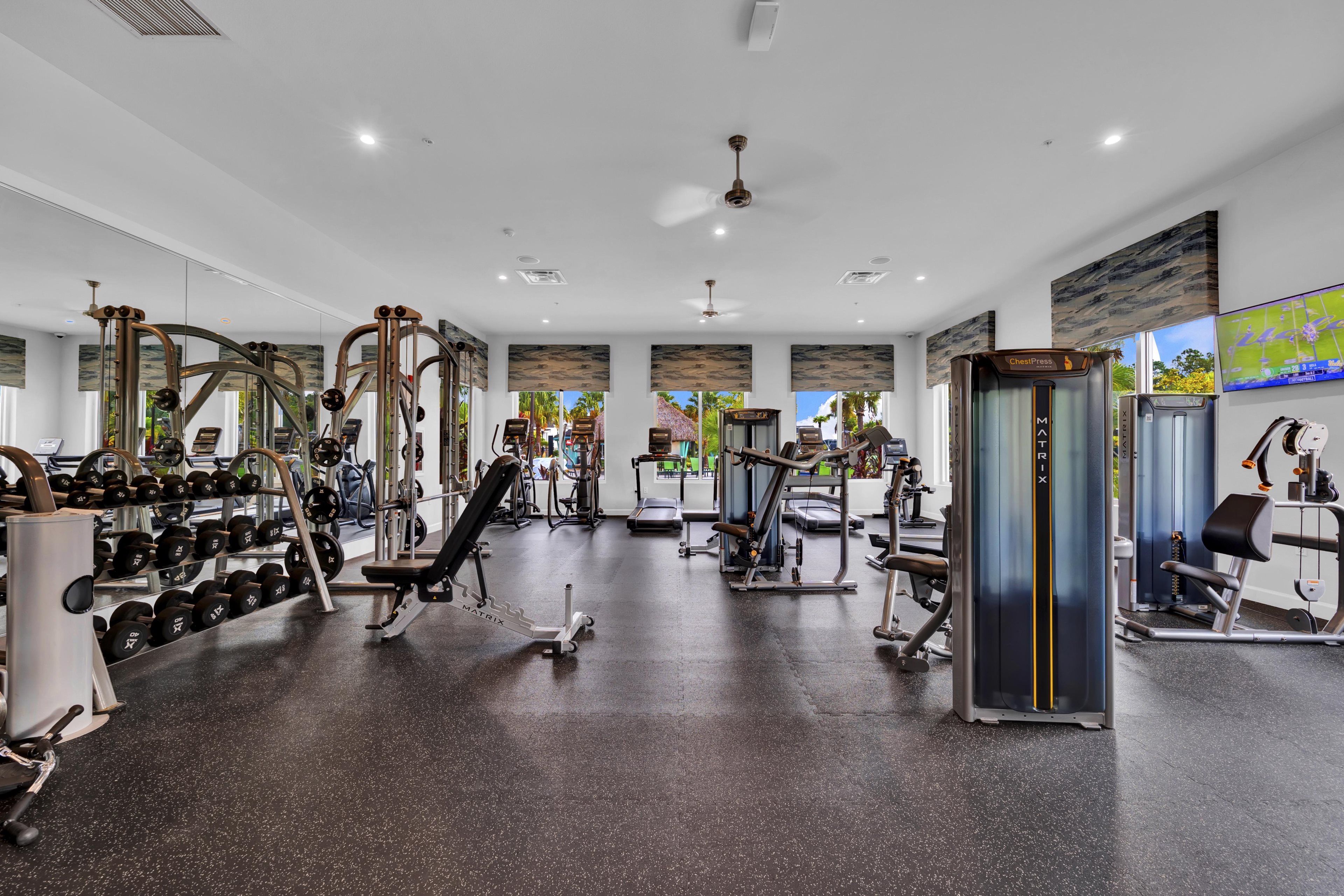 A gym with various exercise equipment, including dumbbells, weight machines, and cardio machines.