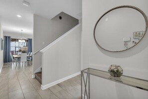 A modern interior with a staircase, a dining area, and a hallway with a decorative mirror. - Private pool, resorts, 9 minutes to Disney (Kissimmee)