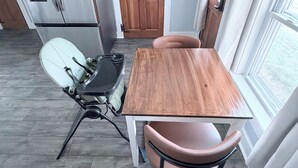Une cuisine compacte avec une table et des chaises en bois, un four encastré et un réfrigérateur.
