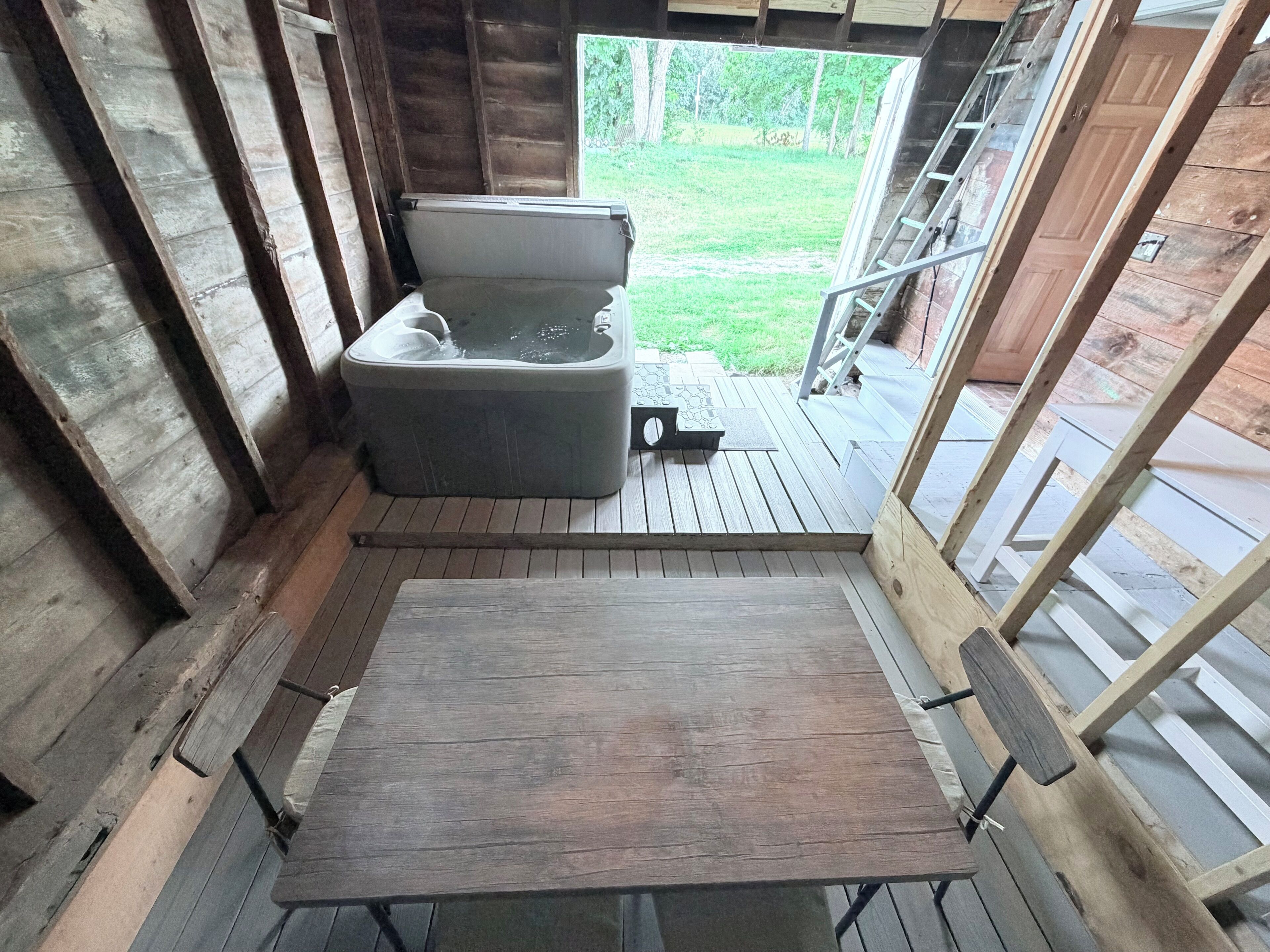 Una terraza de madera con un jacuzzi y una mesa de madera.