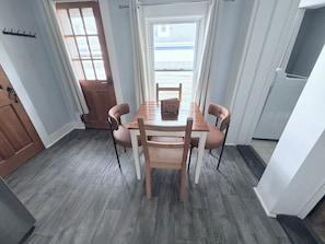 Un comedor con una mesa y sillas de madera, una ventana con cortinas y una puerta.