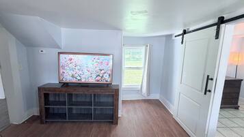 A room with a wooden entertainment center, a large painting, a window with curtains, and a sliding door.