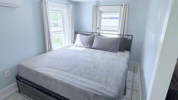 A bedroom with a bed, a ceiling light, and a window with curtains.