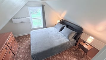 Un dormitorio con cama, cómoda, mesita de noche y ventana con cortinas.