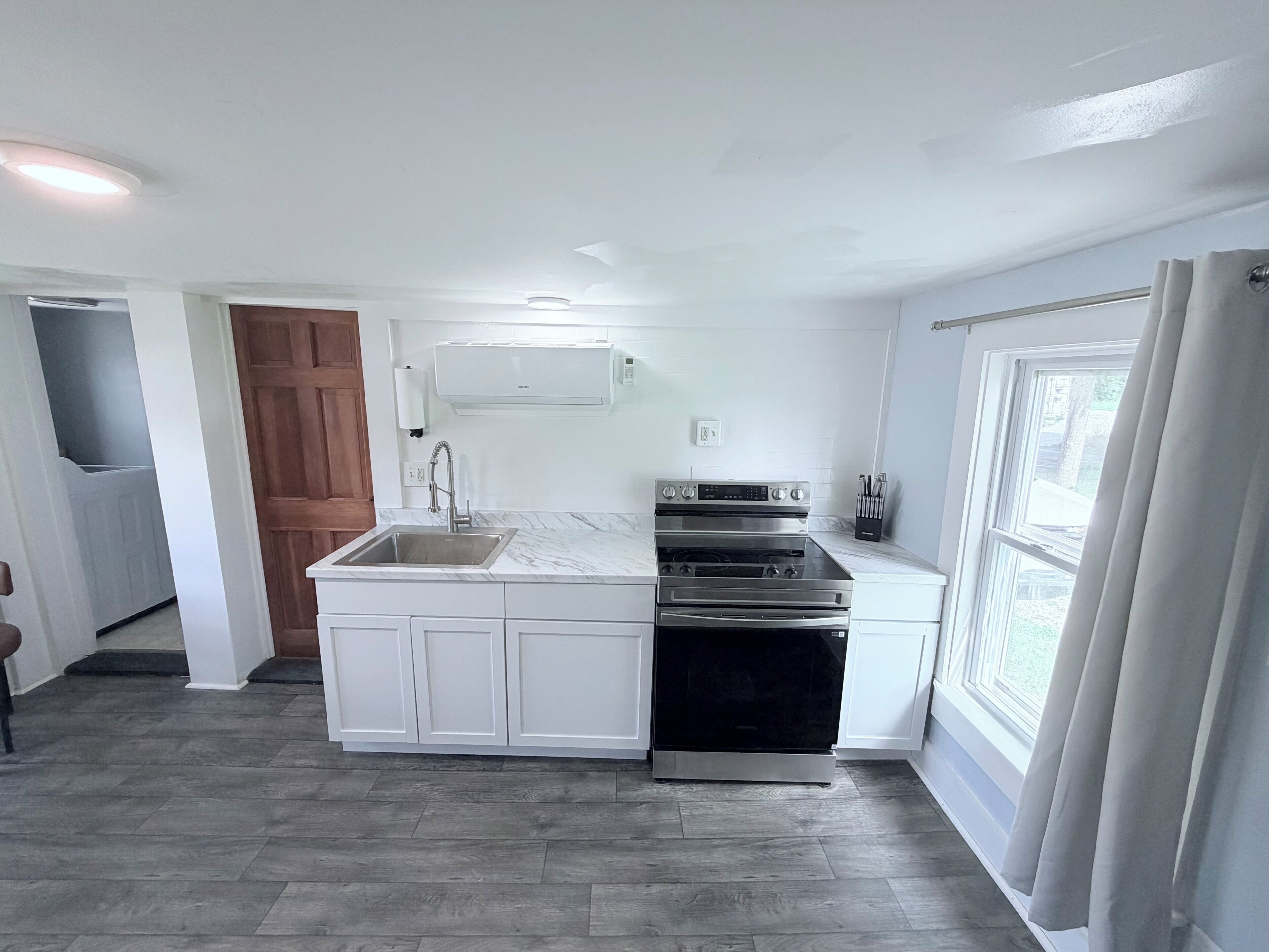 A kitchen with white cabinetry, a built-in oven, and a sink.