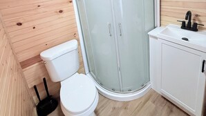 Une petite salle de bain comprenant des toilettes, une douche à parois de verre et un lavabo avec un miroir au-dessus.