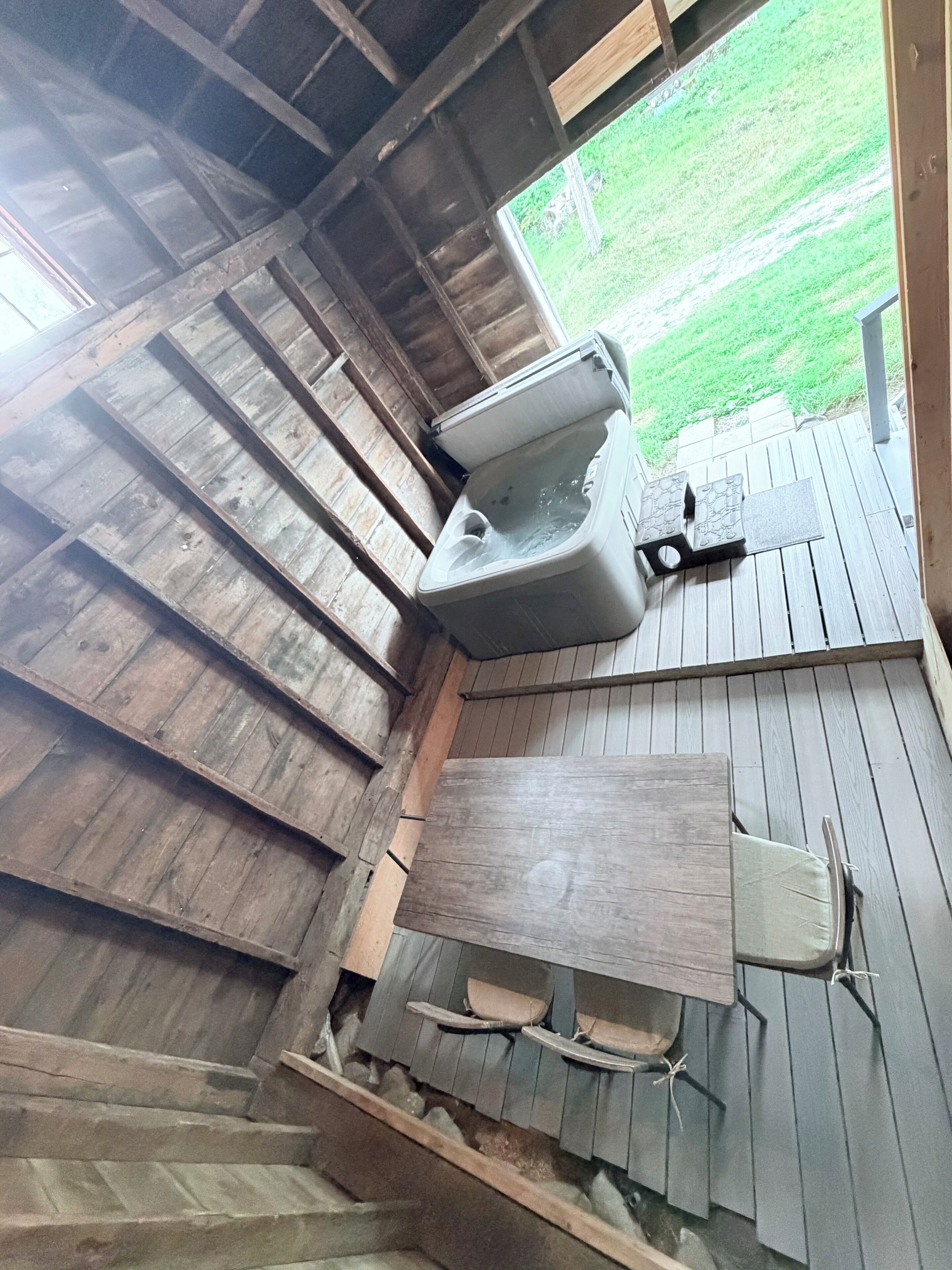 A rustic wooden bathroom with a built-in toilet, a wooden bench, and a small window.