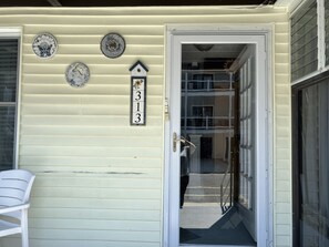 A house with a number sign, decorative plates, and a white chair outside. - Lovely 1-bedroom condo with pool in lovely Wildwood right by beach and boardwalk (Wildwood)