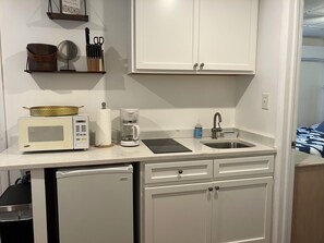 Uma cozinha compacta equipada com micro-ondas, cafeteira e pia.
