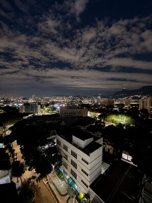 Une vue nocturne d’une ville, avec ses bâtiments, un ciel dégagé et une montagne lointaine.