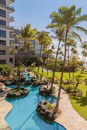 Un resort con piscina, palme e vista sull'oceano.