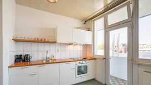 Una cocina con armarios blancos, encimera de madera, un lavabo, cafetera y horno.