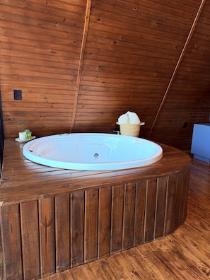 Ein hölzernes Whirlpool in einem Raum mit schrägen Holzwänden.