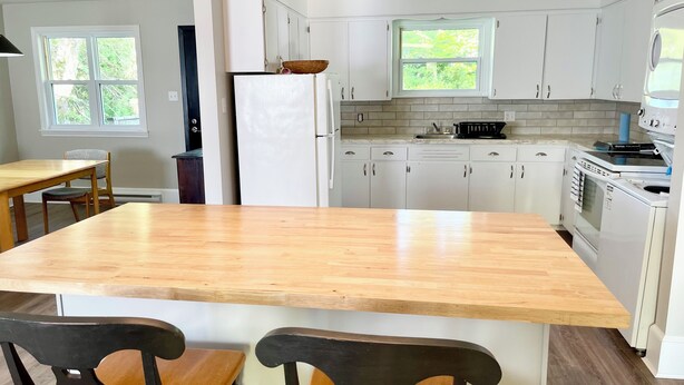 A kitchen with white cabinets, a wooden island, and a built-in oven.