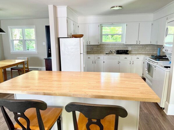 A kitchen with white cabinets, a wooden island, and a built-in oven.