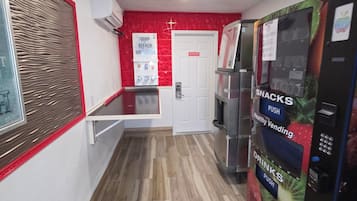 A hallway with a vending machine offering snacks and drinks, a door, and a wall-mounted air conditioner.