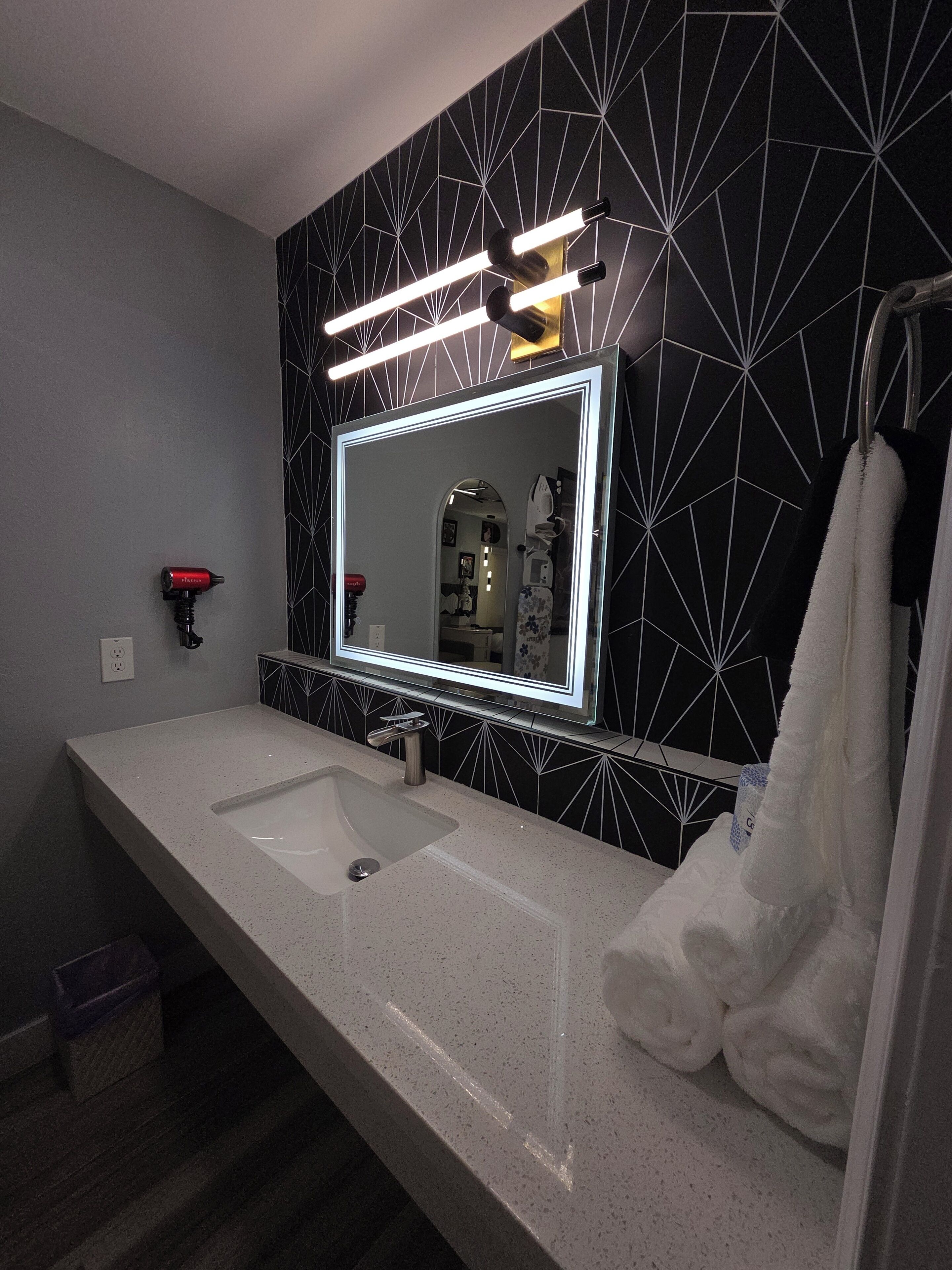 A bathroom with a large mirror, two sinks, and a towel rack.