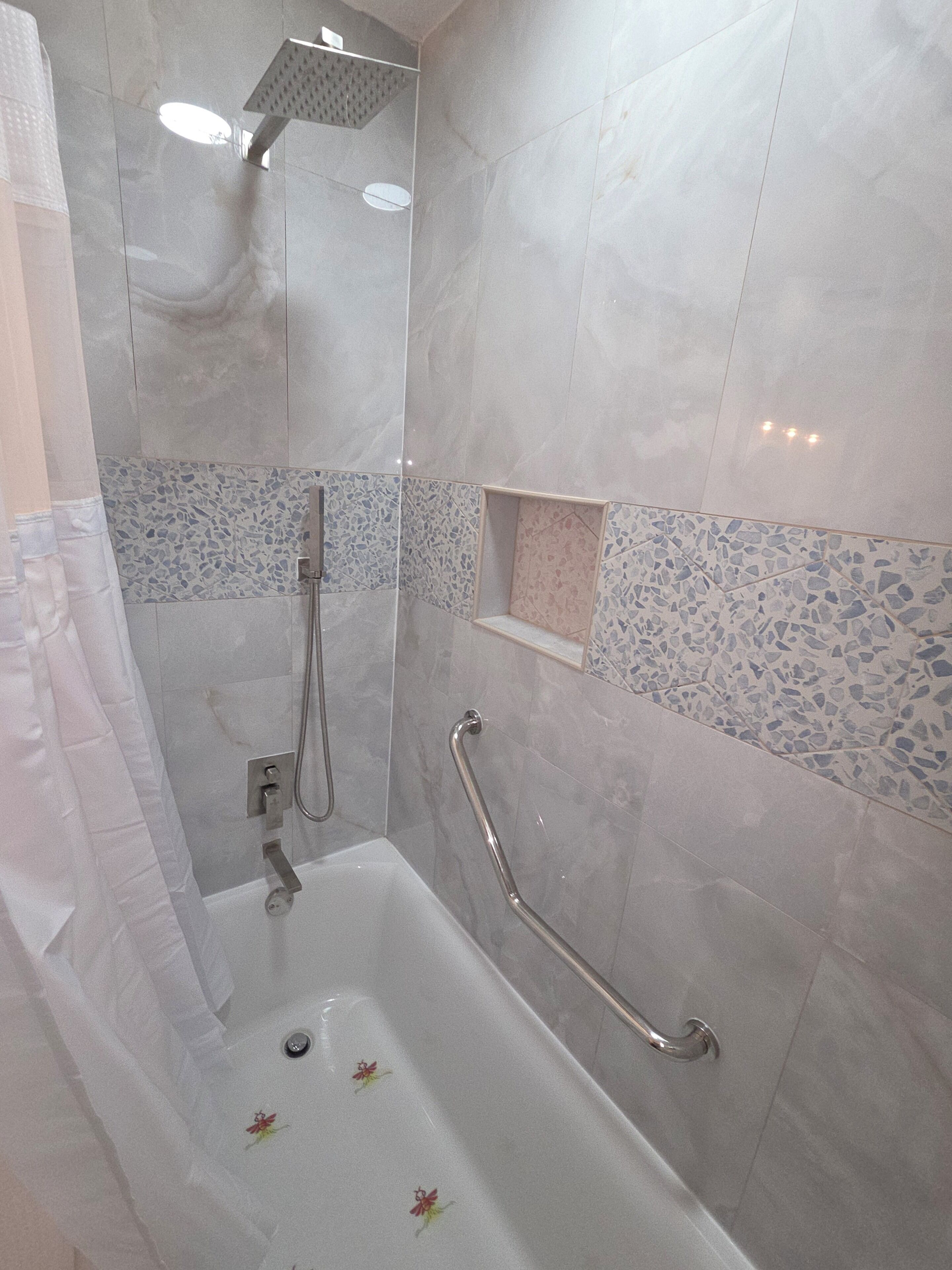 Un baño con bañera, ducha y barra de apoyo.