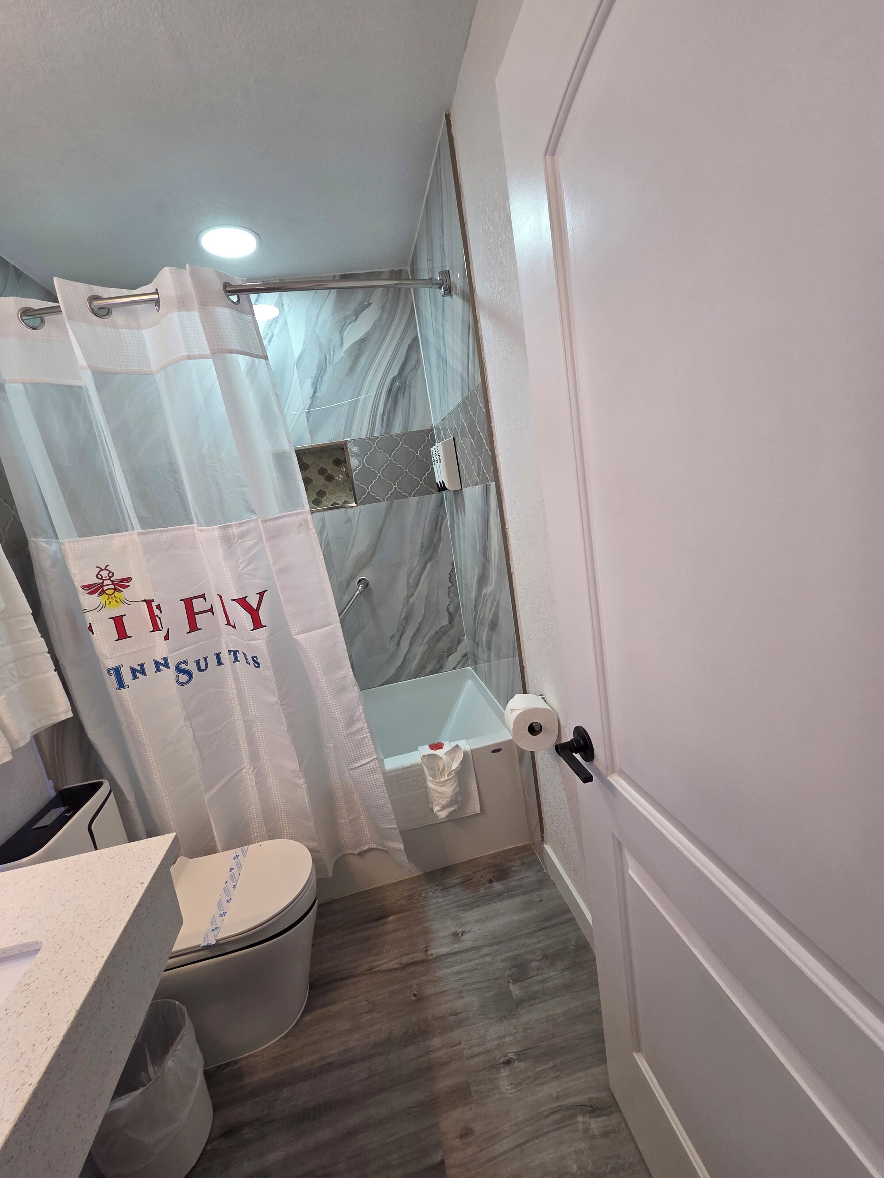 A bathroom with a shower, toilet, and a towel rack.