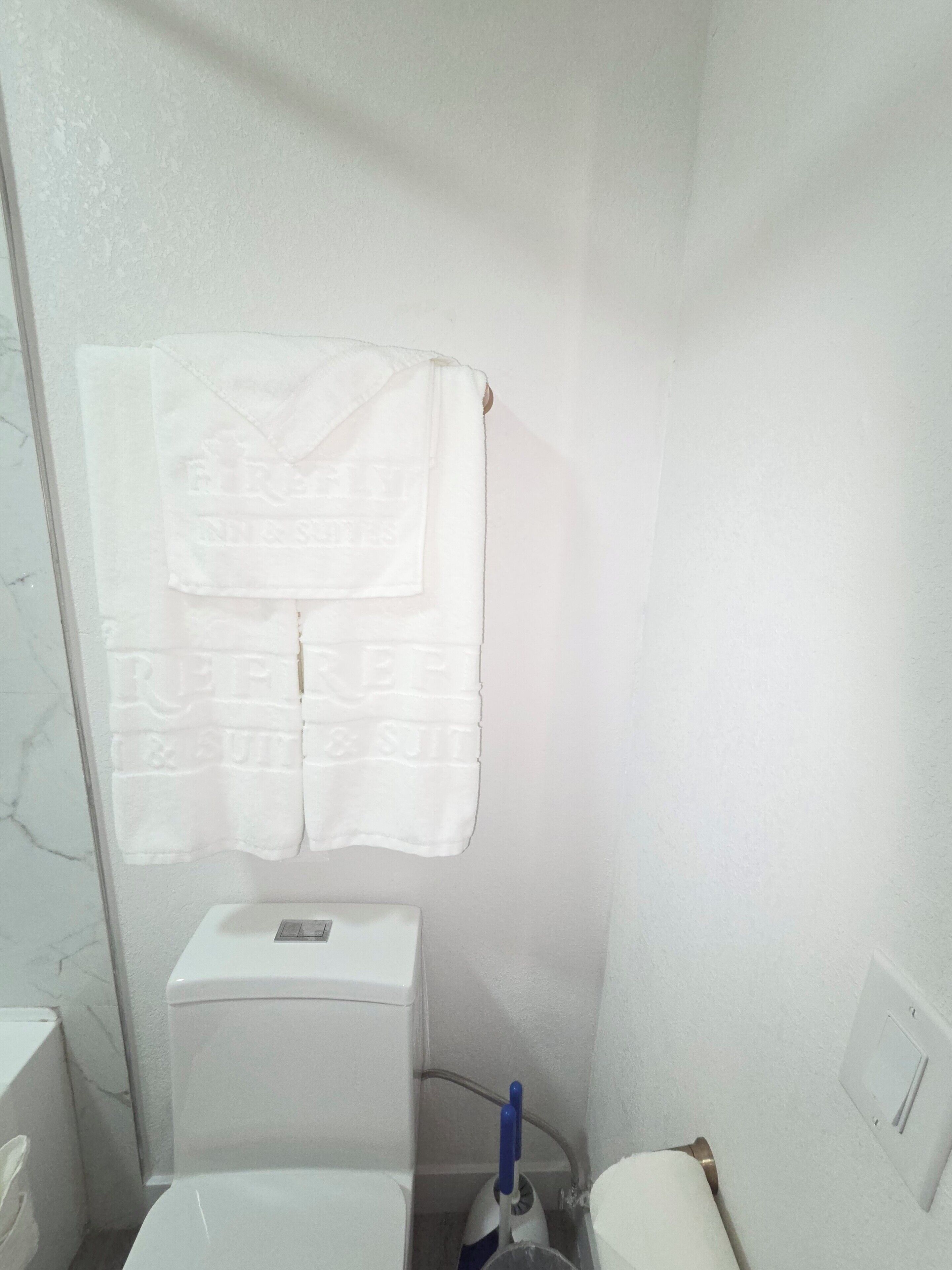Un baño pequeño con inodoro, lavamanos y una toalla colgada en la pared.