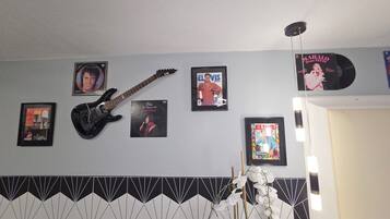 A room with a guitar, framed Elvis Presley memorabilia, and a patterned wall.