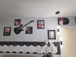 Una habitación con una guitarra, recuerdos enmarcados de Elvis Presley y una pared con diseño.