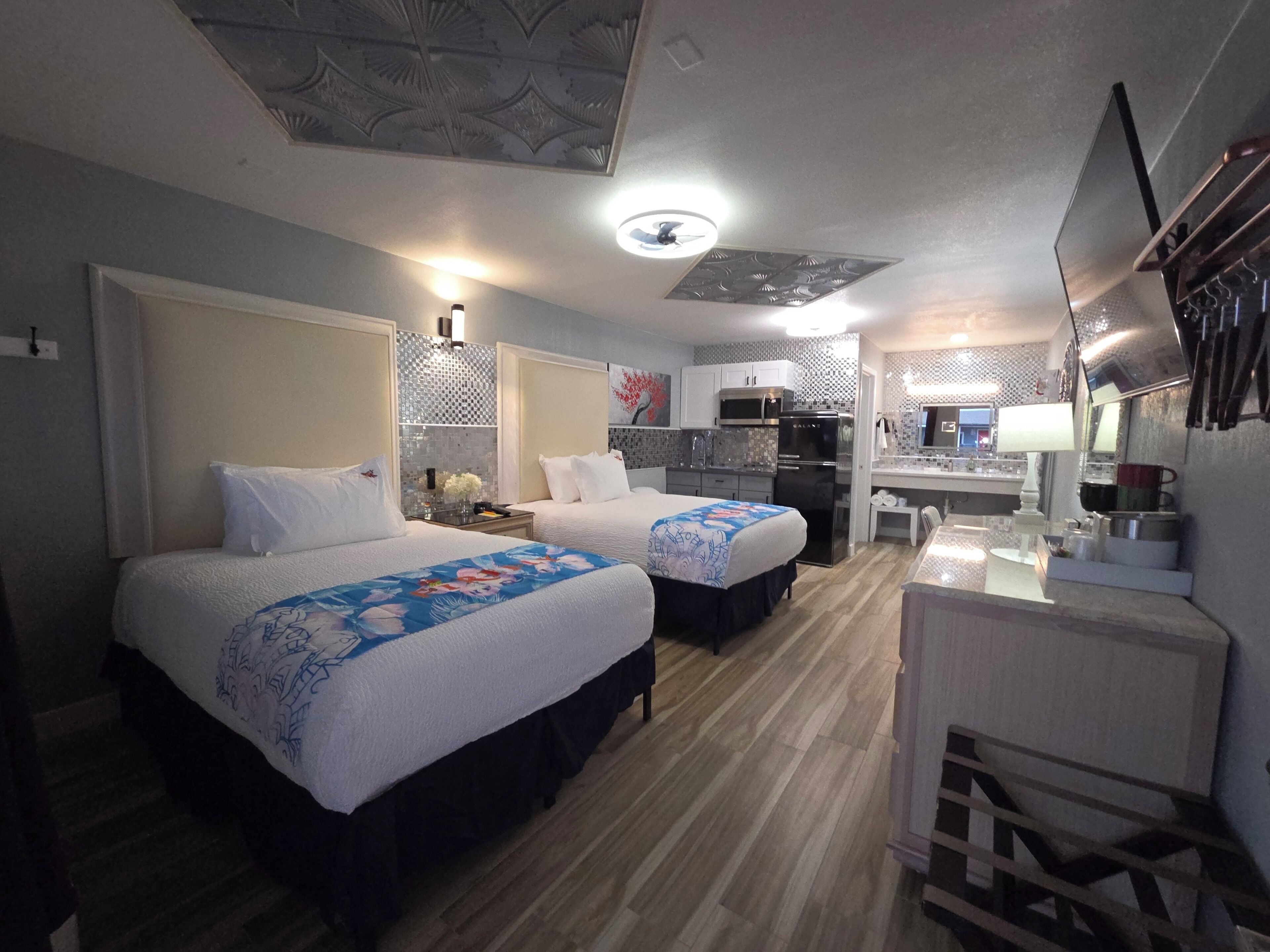 Een hotelkamer met twee bedden, een kitchenette, een bureau en een badkamer.