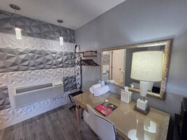 Un baño moderno con un revestimiento de pared con diseño geométrico, un espejo grande, un perchero y una revista sobre la encimera.