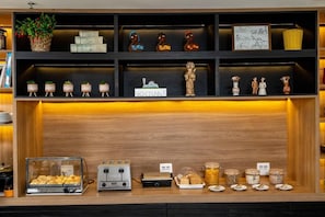 A breakfast bar with a variety of pastries, a coffee machine, and a display of jars.