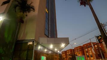 Um edifício moderno com uma estrutura vertical marcante e uma entrada bem iluminada.