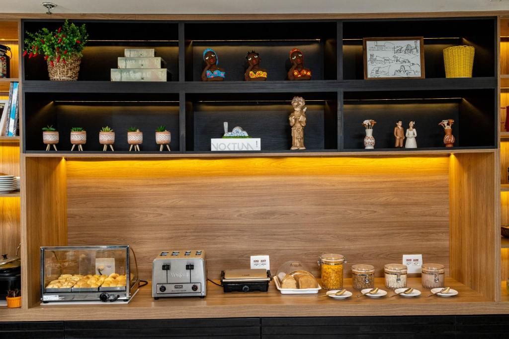 Um balcão de pequeno-almoço com diversos pastéis, uma máquina de café e uma exposição de frascos.