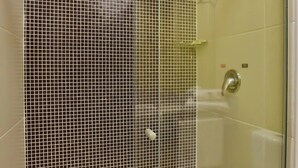 Un baño moderno con cabina de ducha de vidrio, una bañera blanca y pared de ducha con azulejos.