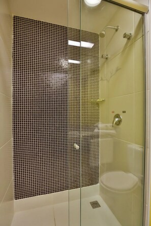 Ein modernes Badezimmer mit Duschkabine aus Glas, einer weißen Badewanne und einer gefliesten Duschwand.
